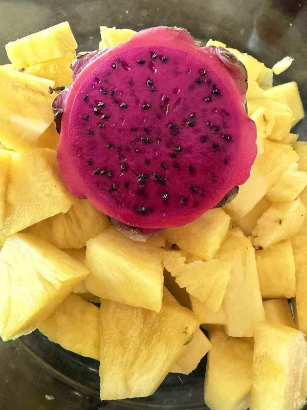 Frische Ananasstücke mit einer aufgeschnittenen pinken Pitahaya
