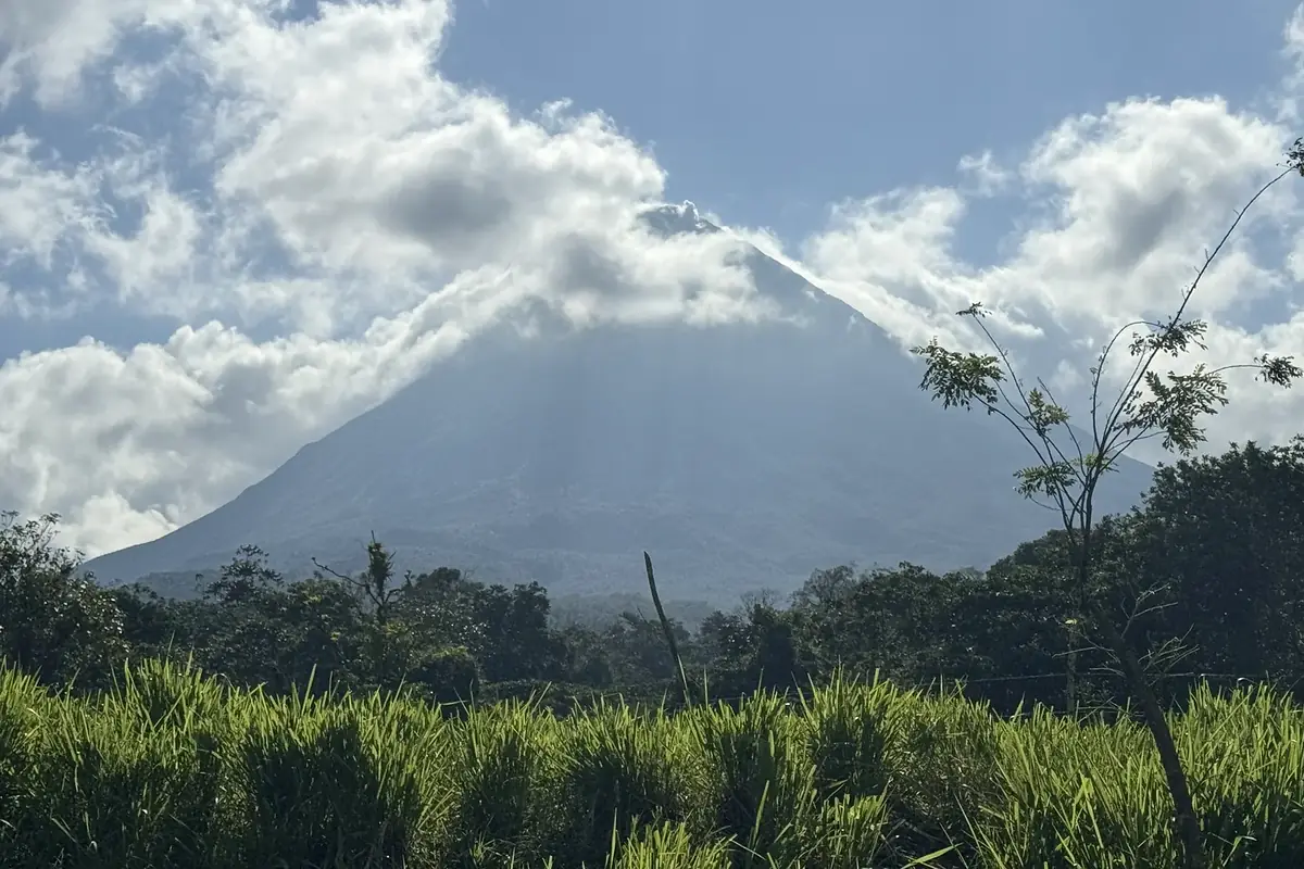 Der Vulkan Arenal mit Wolken über grünen Feldern